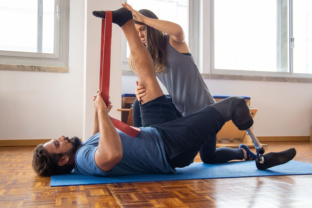 A physiotherapist guiding a patient through a resistance band stretch on a mat